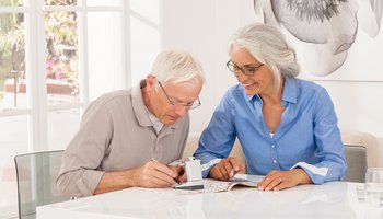 Das Foto zeigt zwei ältere Menschen, die gemeinsam mit scribolux Kreuzworträtsel lösen.