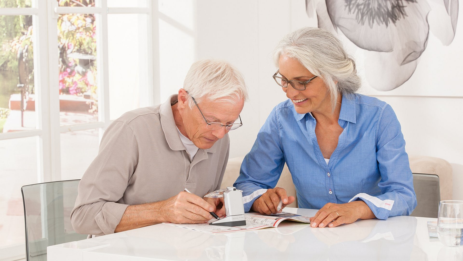 Das Foto zeigt zwei ältere Menschen, die gemeinsam mit scribolux Kreuzworträtsel lösen.