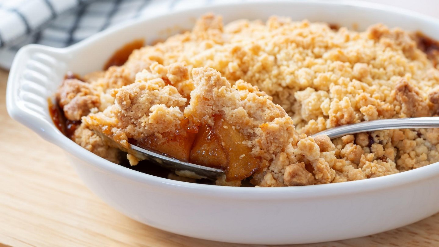 Frisch gebackener Apfelkuchen mit knusprigen Streuseln in weißer Auflaufform