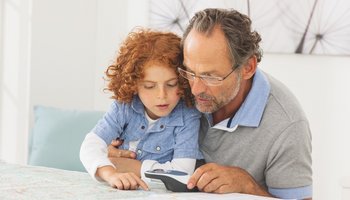 Das Bild zeigt einen älteren Herrn, der gemeinsam mit einem Kind mit der Leuchtlupe eine Landkarte liest.