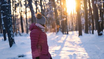 Das Foto zeigt eine Frau beim Winterspaziergang in der Sonne.