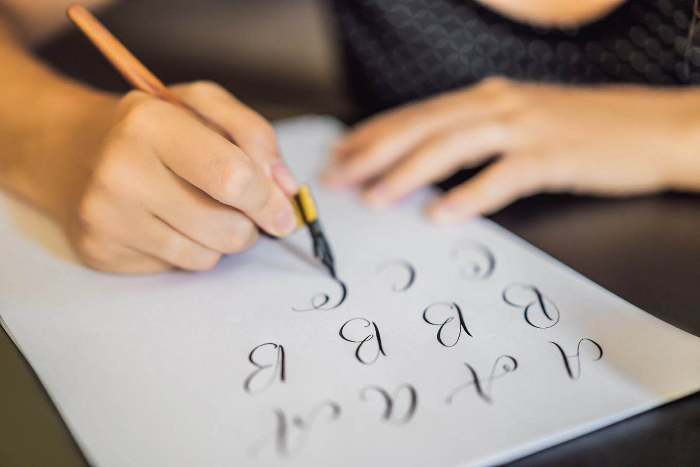 Das Foto zeigt die Hände einer Person, die mit einem Füllfederhalter Handlettering betreibt.