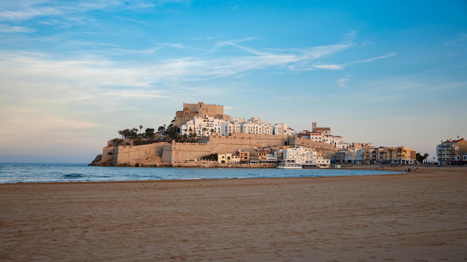 Panoramablick auf die charmante Küstenstadt Peniscola in Spanien, die noch nicht von Touristen überlaufen ist, mit der historischen Festung auf einem Hügel, umgeben von weißen Gebäuden und einer ruhigen Strandpromenade.