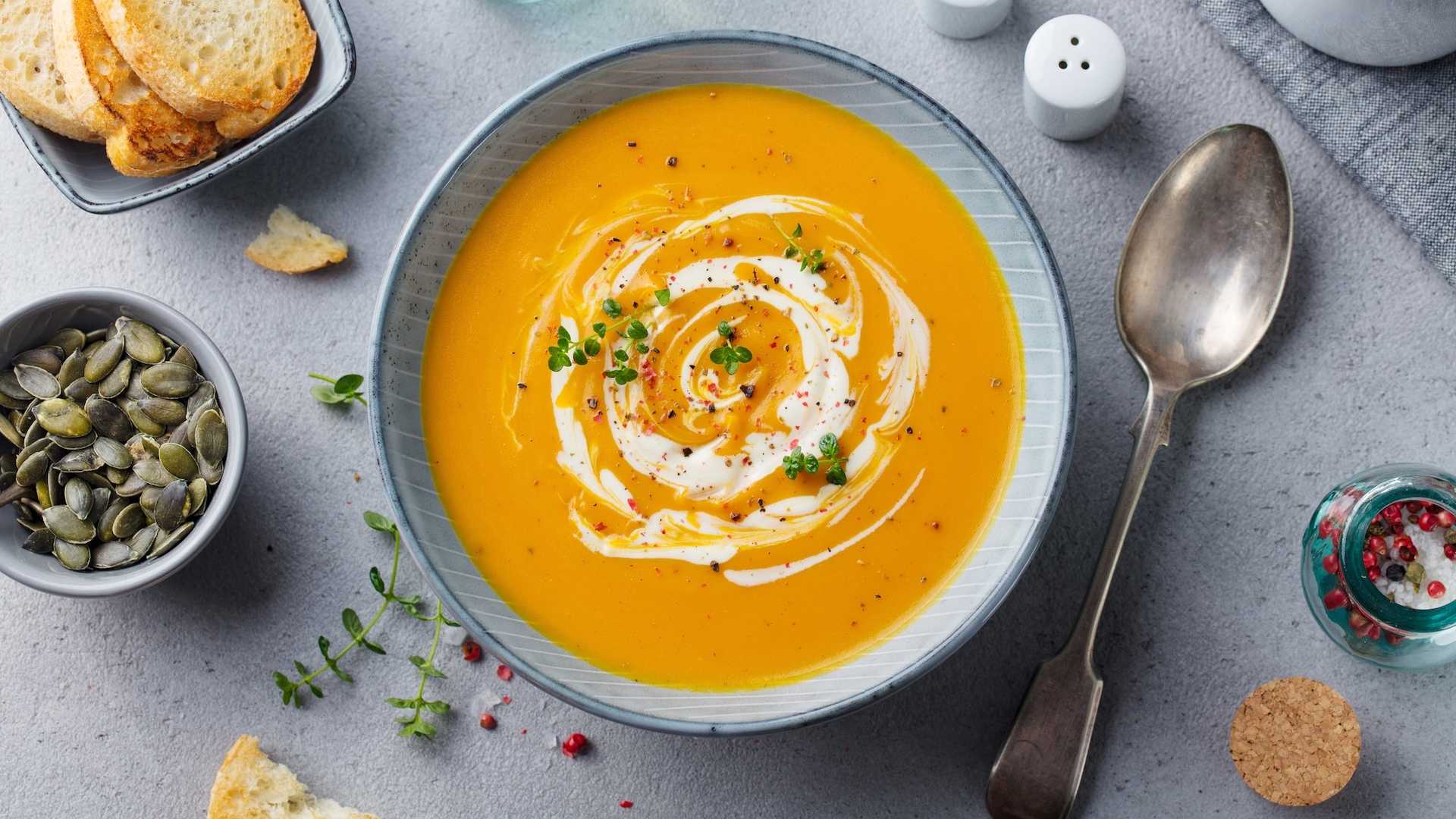 Cremige Kürbissuppe mit Sahne und frischen Kräutern garniert